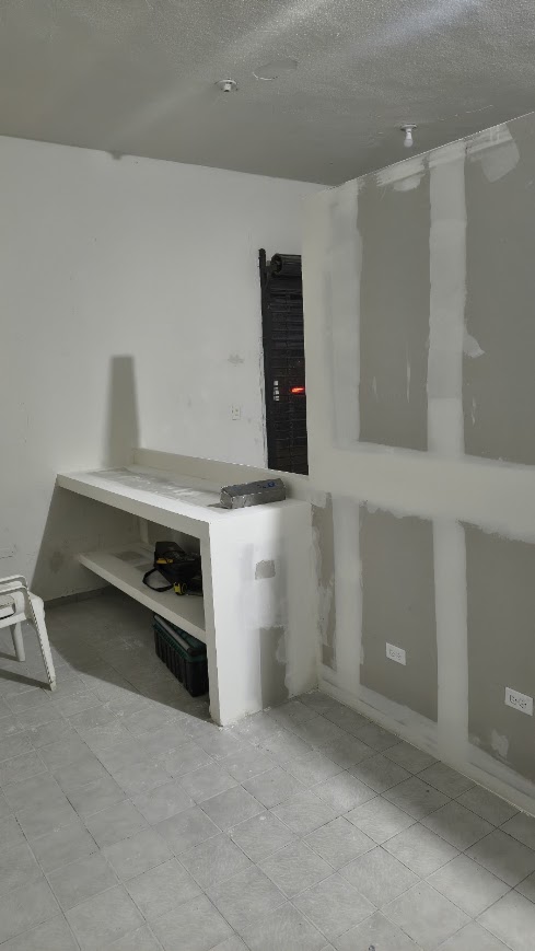 Barra de tablaroca en construcción junto a tablero eléctrico en local comercial
